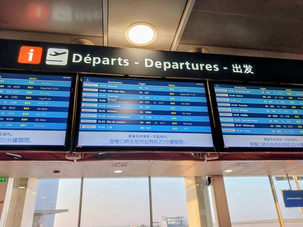 Flight departure information board showing various destinations, flight numbers, and statuses at an airport.