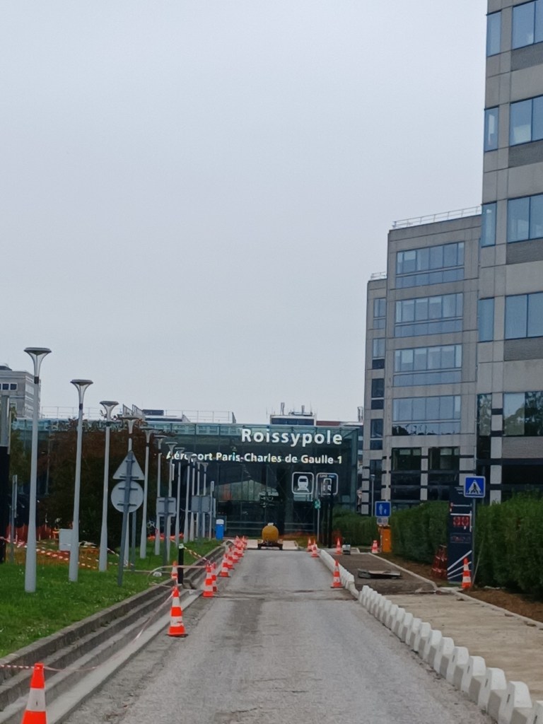 View of Roissypole, the transport hub for Charles de Gaulle Airport, featuring construction barriers and a cloudy sky.