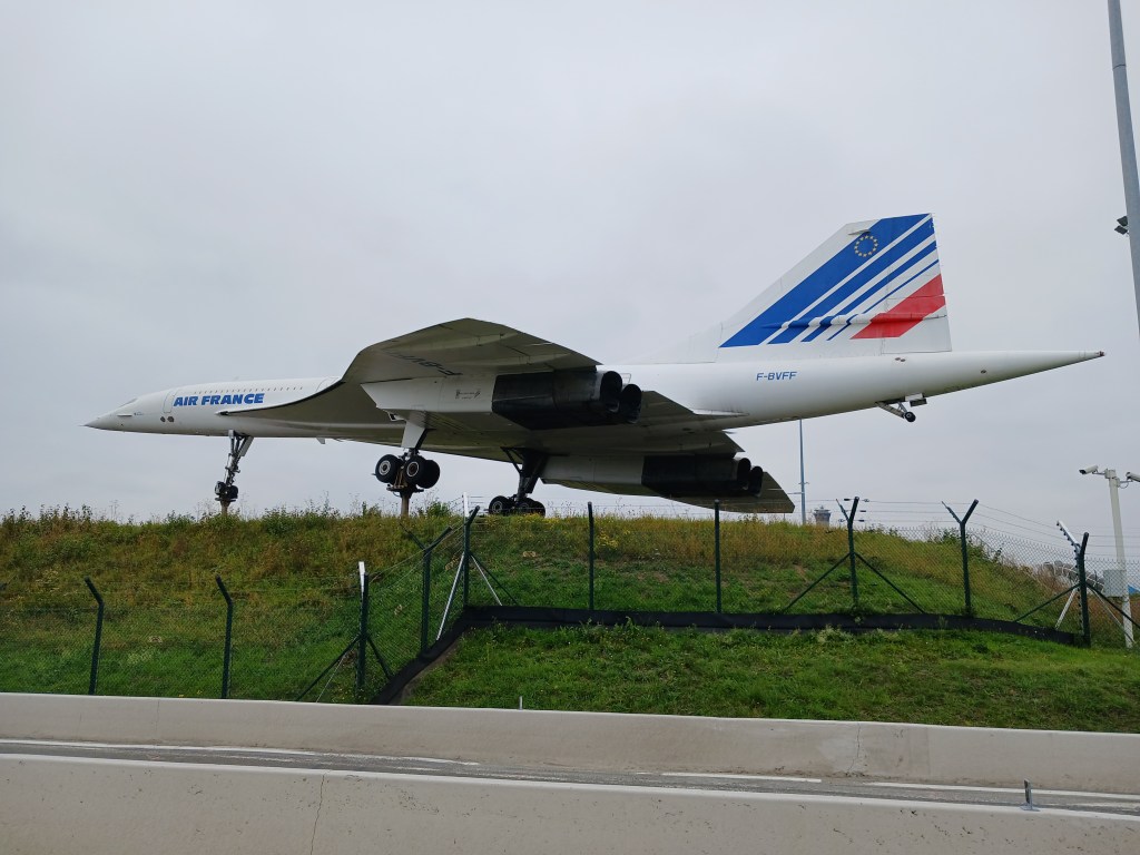 A Concorde aircraft displayed on a grassy area near an airport, painted in Air France livery.